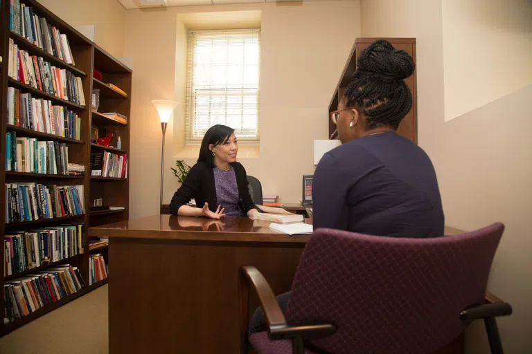 A student sitting across from a faculty member during office hours.