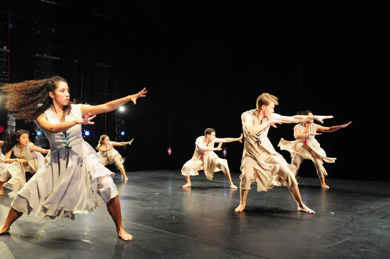 Students dancing on stage in white.