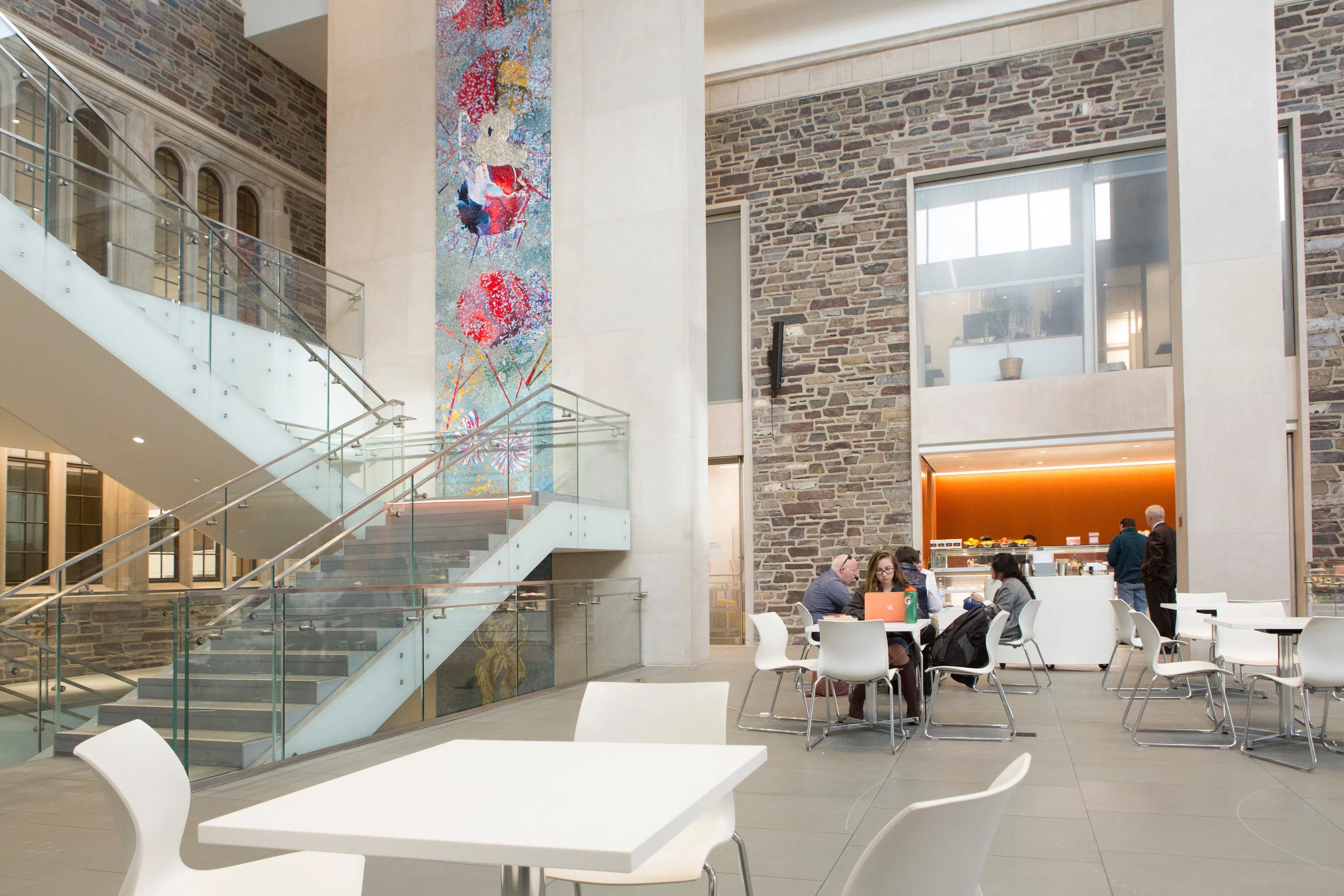 Staircase through building foyer with students working in cafe below.