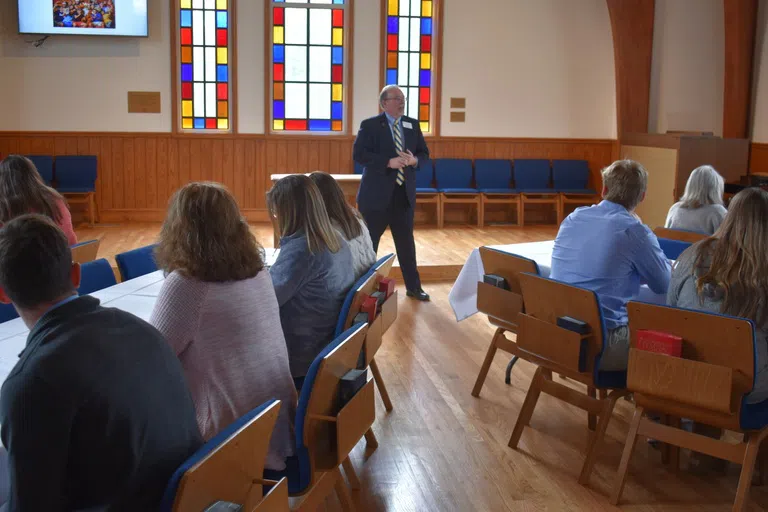 Group meeting in Jones Chapel sanctuary with stained glass windows.