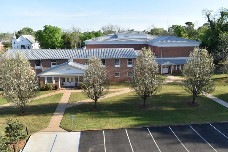 Exterior image of entrance to Parker Athletic Building with trees and lawn.