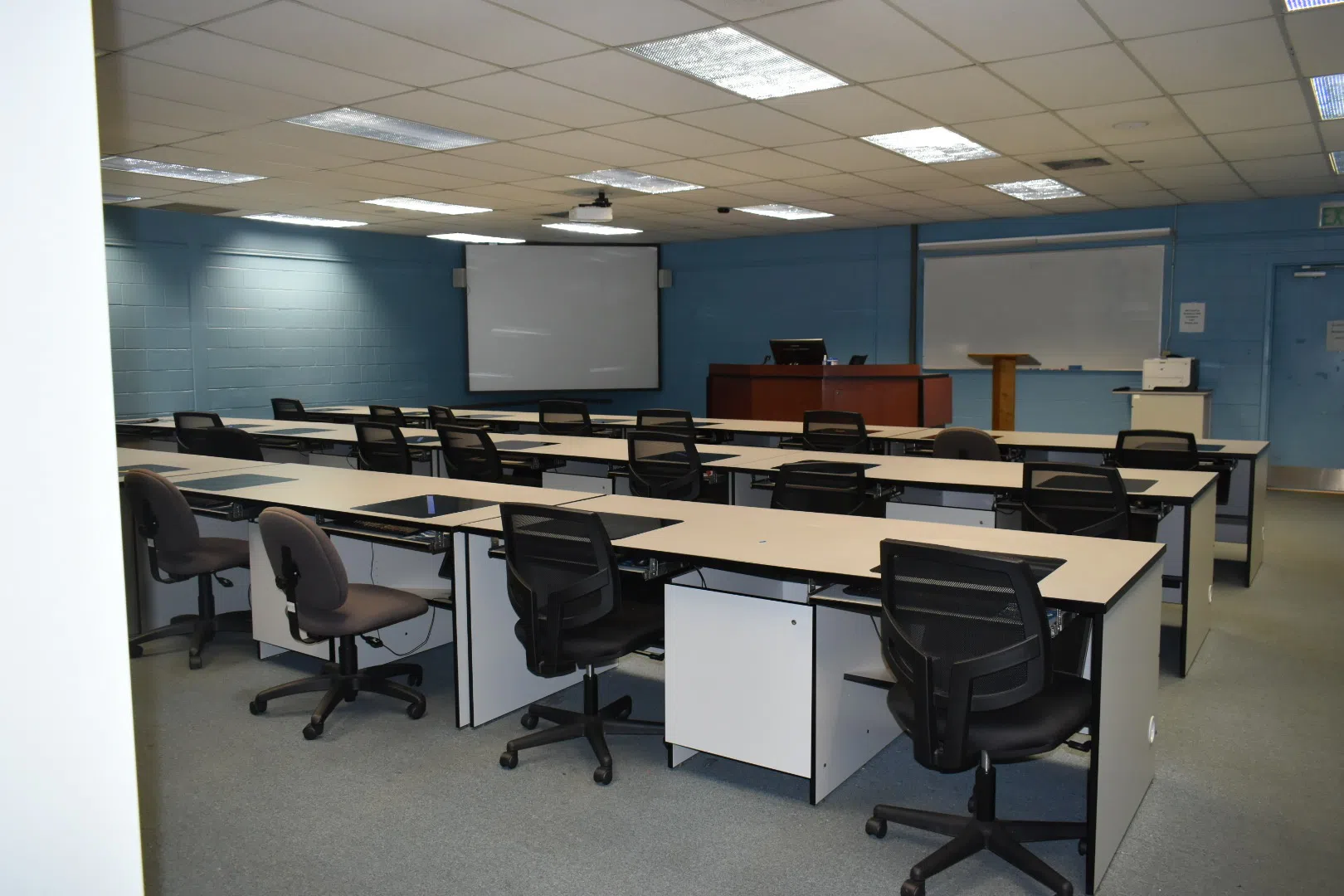 Image of empty classroom with desks, chairs , computers and screens located in Pitts Library.