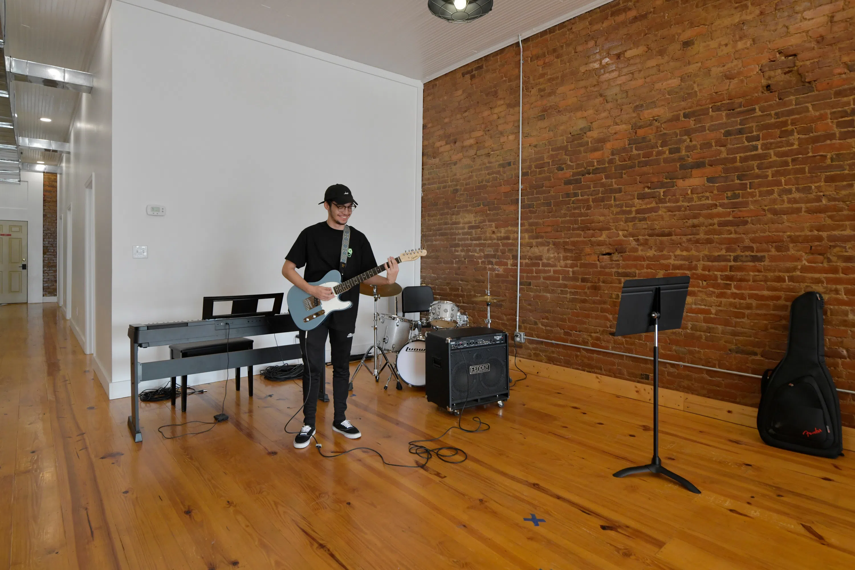 Image of a male student smiling and practicing guitar.