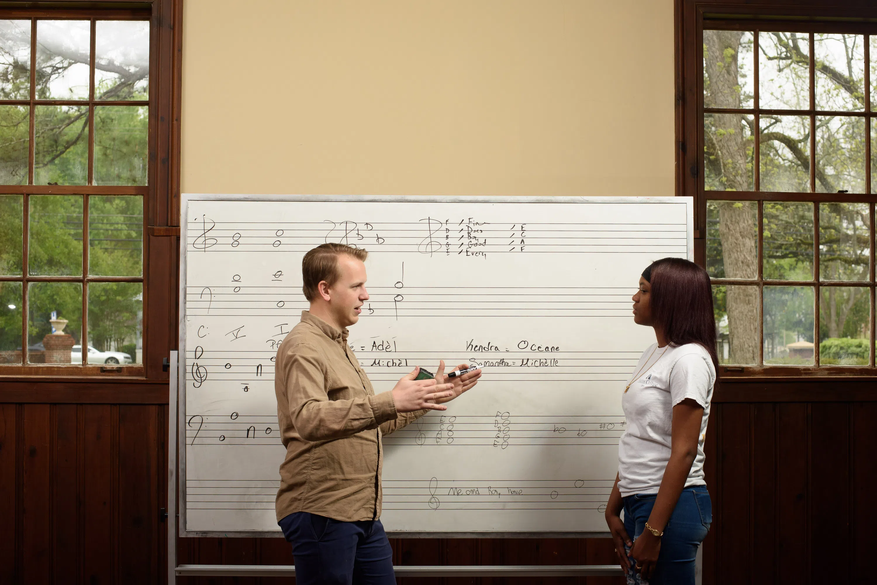 Professor Kolan and music student in Suarez Music Building in front of large whiteboard with music notes.