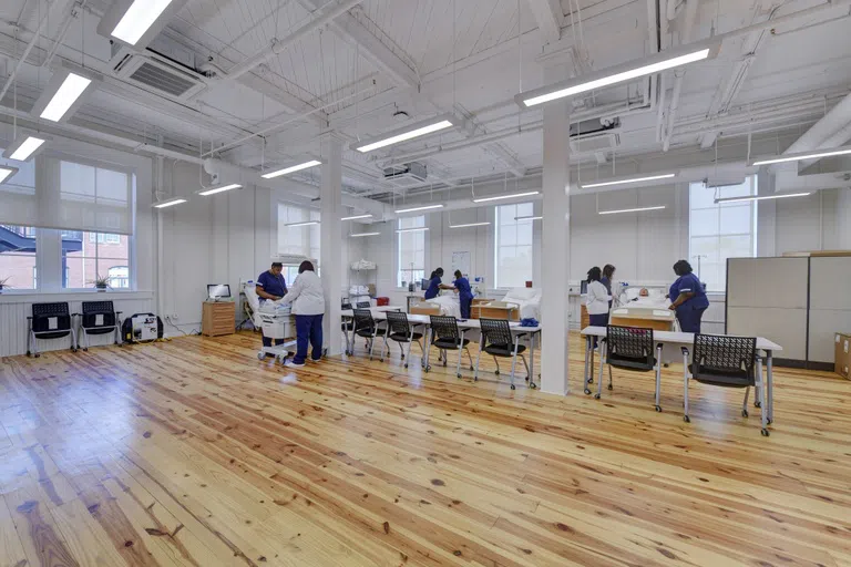 Photo of large room simulation lab with students and nursing equipment.