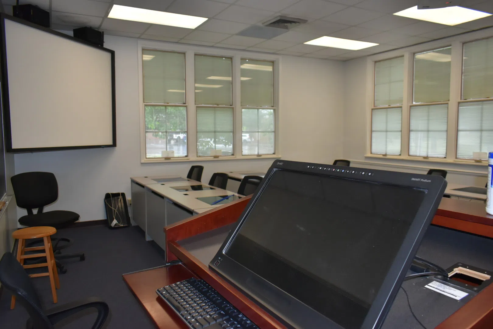 Image of empty classroom from the front of the room overlooking desks with computers and chairs.