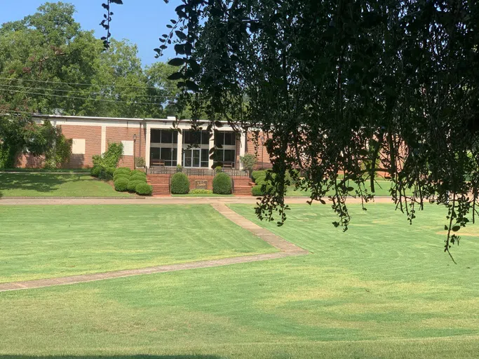 Exterior image of Pitts Library with tree overhang and front lawn.