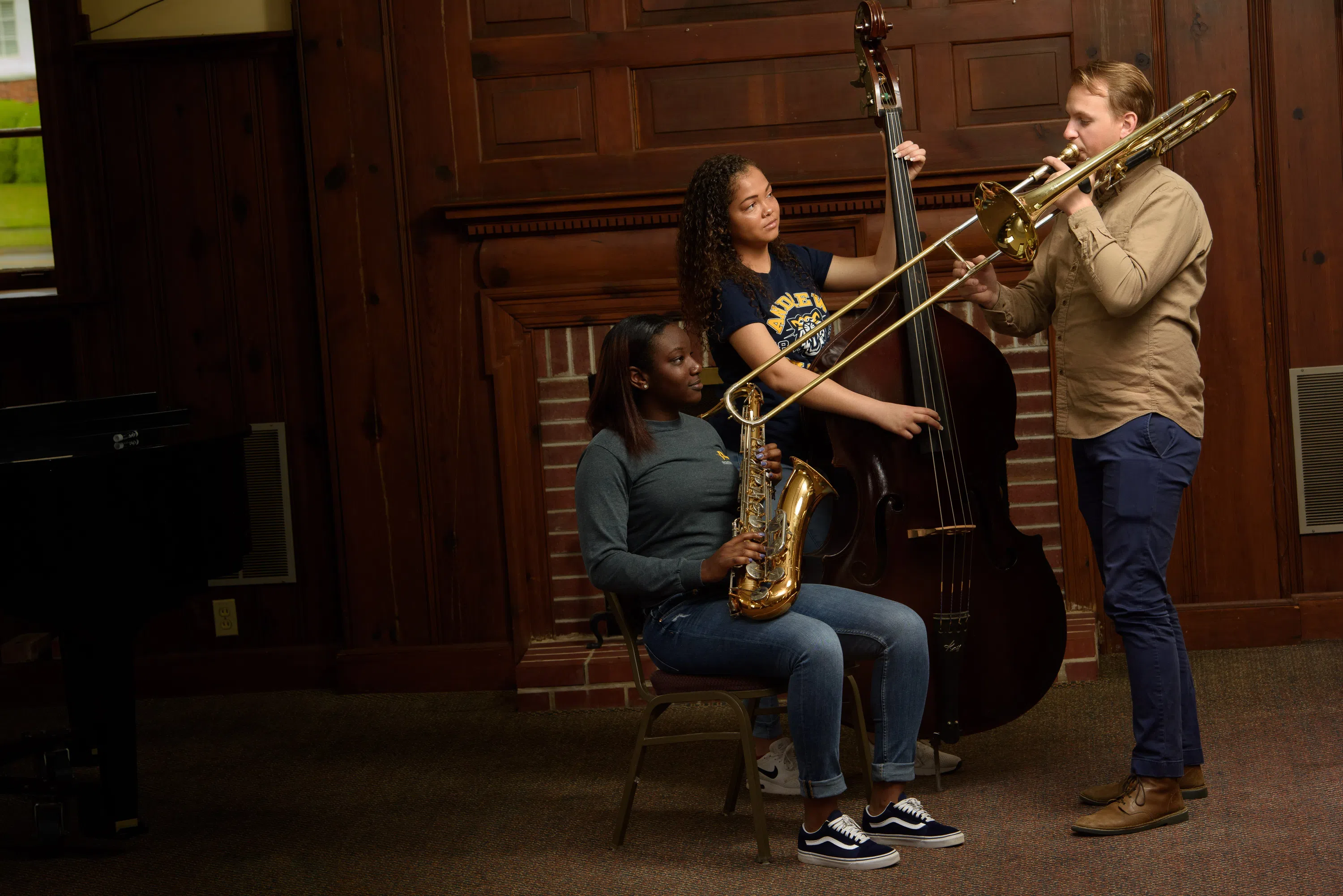 Two female students with professor practice musical instruments.