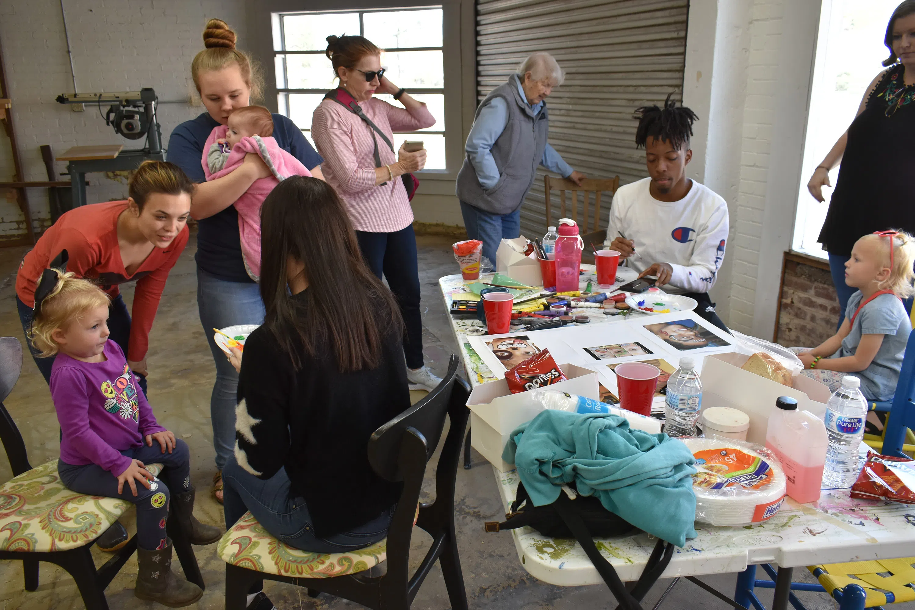 Image of Andrew College students face painting with local children during a recent activity in the theatre set design building.