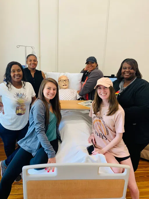 Nursing students posing in the Sim Lab located in the Aderhold Division of Nursing inside Staples Hall.