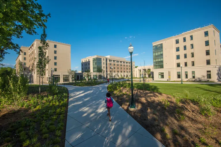 A student walks through East Campus with the Don Myers Technology and Innovation Building in the background.