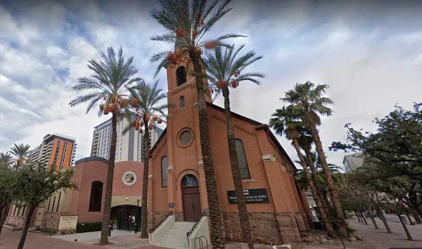 Brick church with steeple, surrounded by palm trees. 