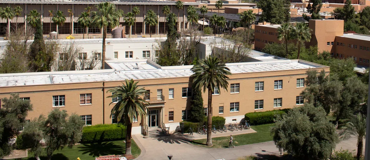 Aerial view of two-story tan building with palm trees in front of entrance