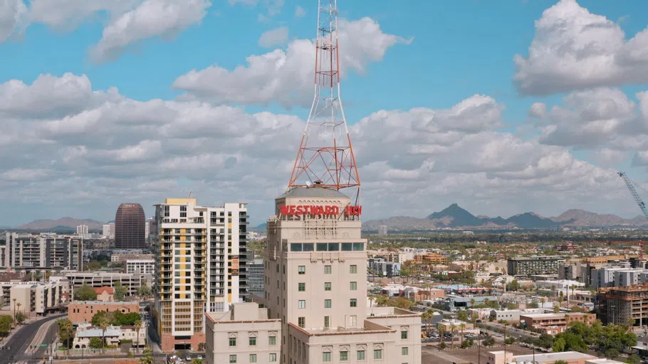 Aerial view of tan multi-story building with a building wide red and white antenna on top and sign saying Westward Ho.