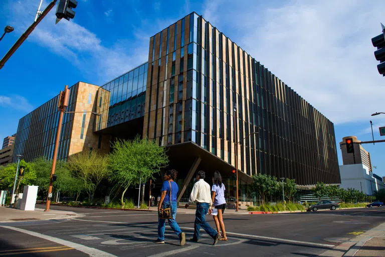 Three people cross the street in front of Beus Center for Law and Society Building.