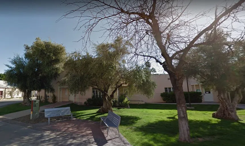 Stucco building with trees in front of it. 