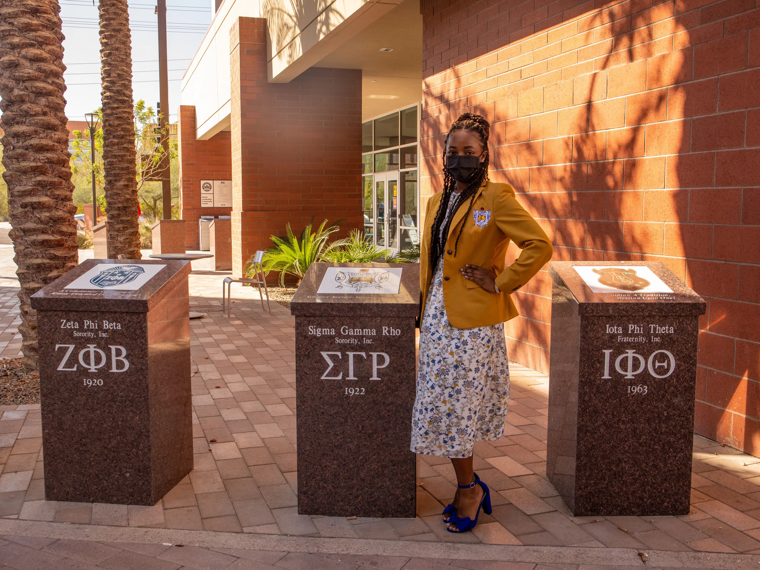 A representative from the Sigma Gama Rho sorority stands next to her society's plaque. 