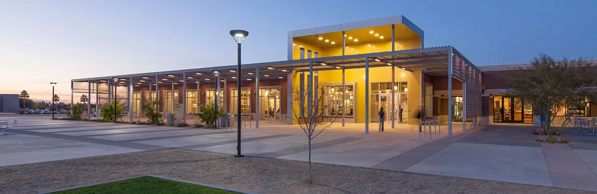 Exterior of building and patio with lights on at dusk.