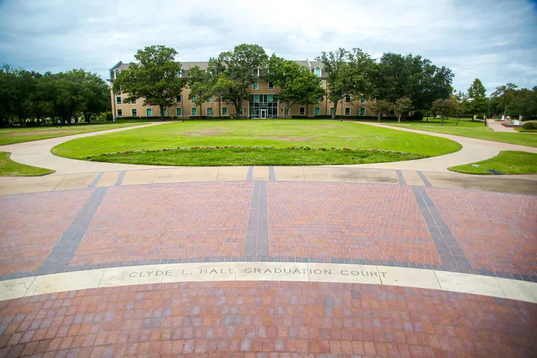 Just north of Caruth Administration Building, brickwork and landscaping mark the Clyde L. Hall Graduation Court.  Clyde L. Hall ’46 joined the Austin College faculty in 1950 and that year was named the holder of the John T. Jones Chair of Economics. In 1977, he became the first occupant of the Clara R. and Leo F. Corrigan, Sr., Chair of Business Administration.  A group of Hall’s former students made financial commitments to name the area in honor of Hall, who retired from the College in 1988. Commencement is held on the site each May.