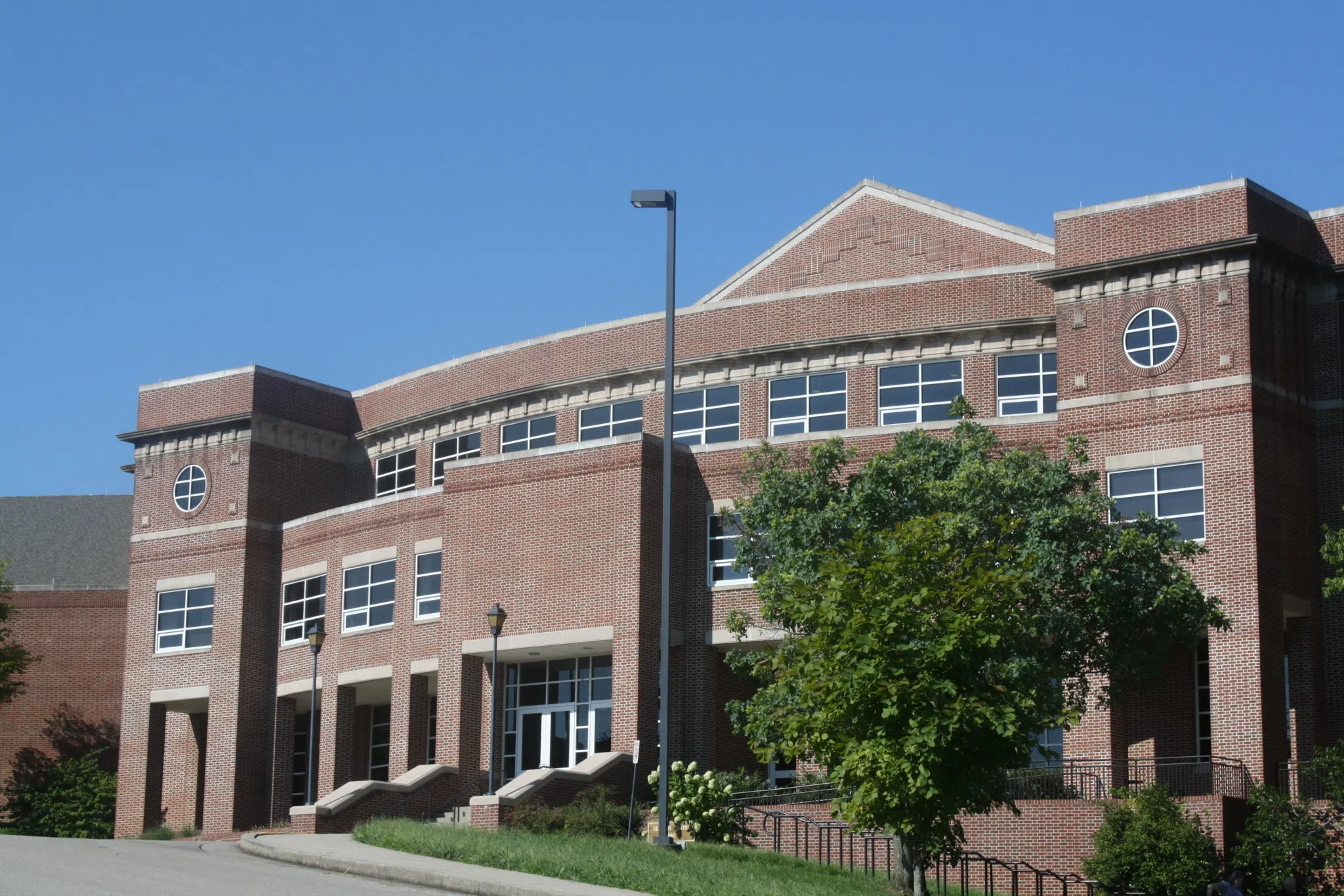  Large modern-looking red brick building with modern lines and large concrete steps. 