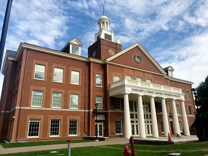 Huge red brick building with large windows and white columned front.