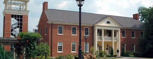 Large red brick building with white columned portico. 