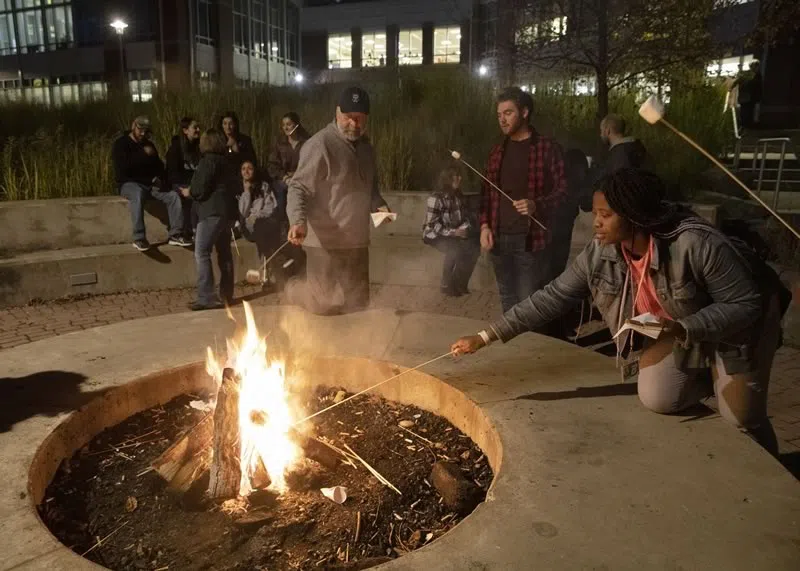 Students roasting marshmallows over the firepit