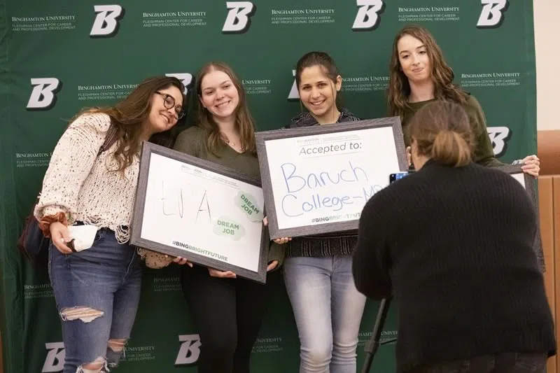 Students taking a photo in front of Binghamton banner