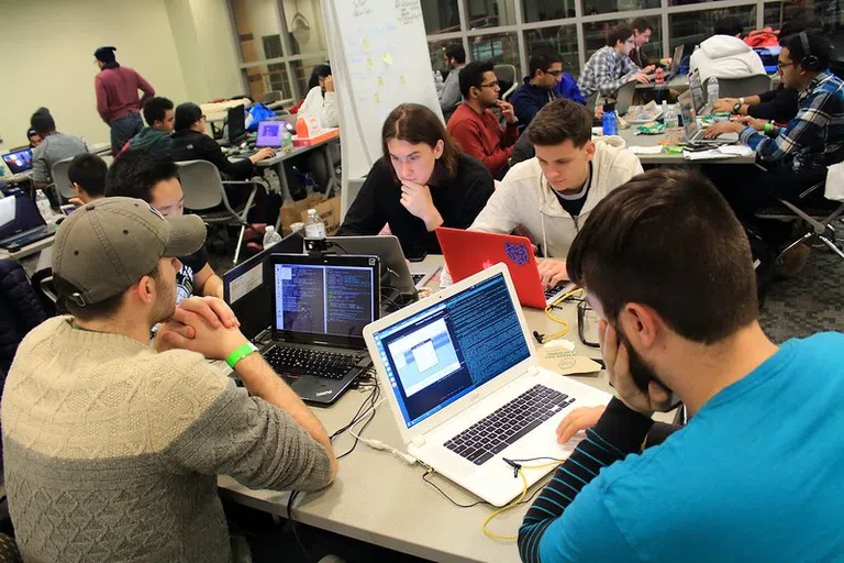 Students work on laptops together as part of Hack Bu