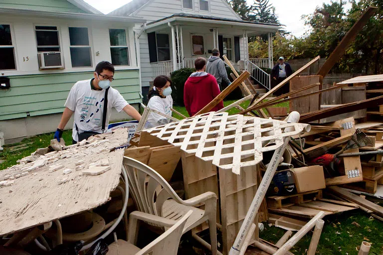 Students participating in volunteer work clearing debris at a construction site.