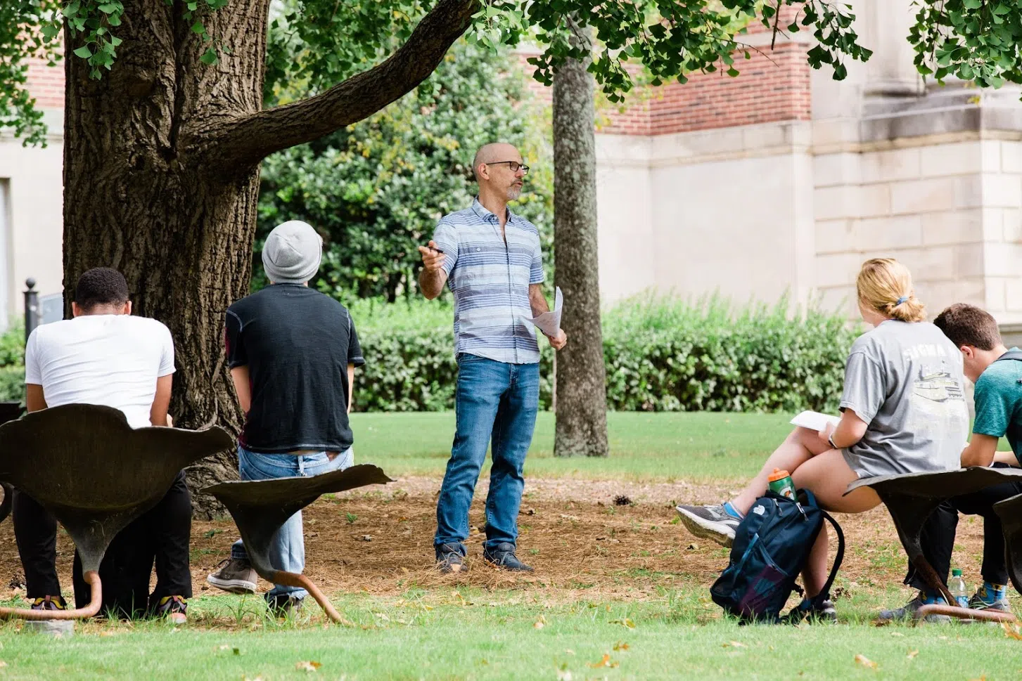 Photo of a faculty member teaching a class in the outdoor classroom under a Ginkgo tree