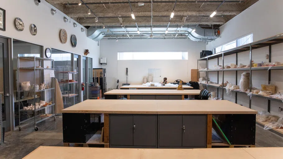 A student works on a Ceramics project by the back wall of a studio