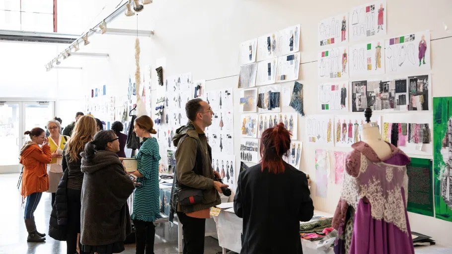 A group of people look at sketches and mood boards pinned up on the wall.