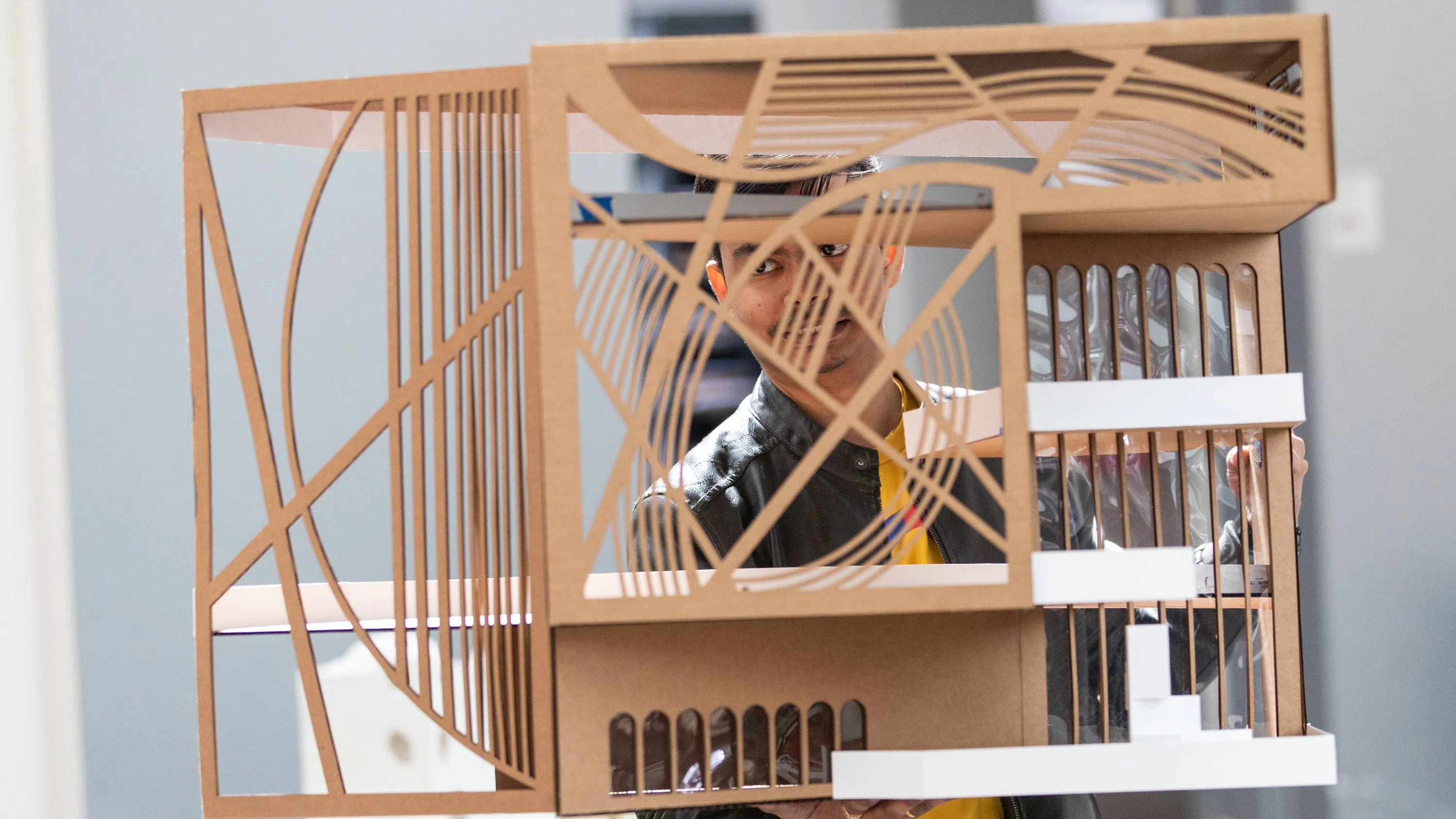 A student holds an architectural model close to his face.