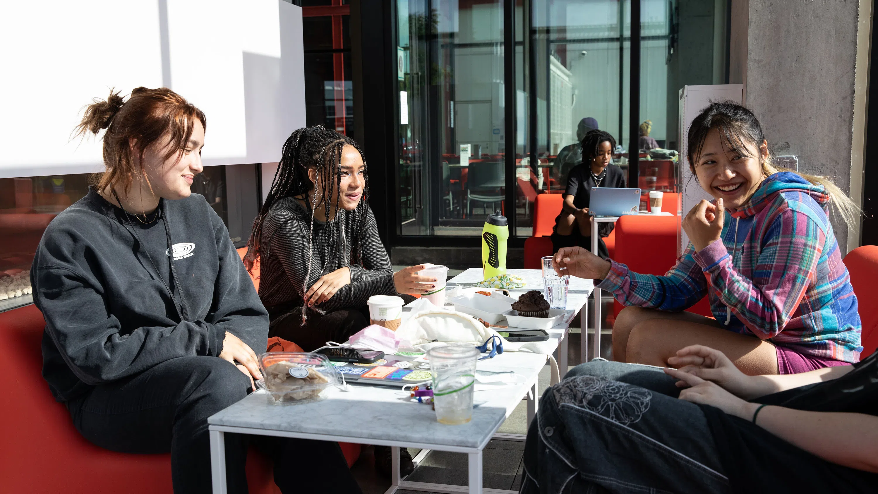 Four students laugh together at a low table in Makers Cafe.