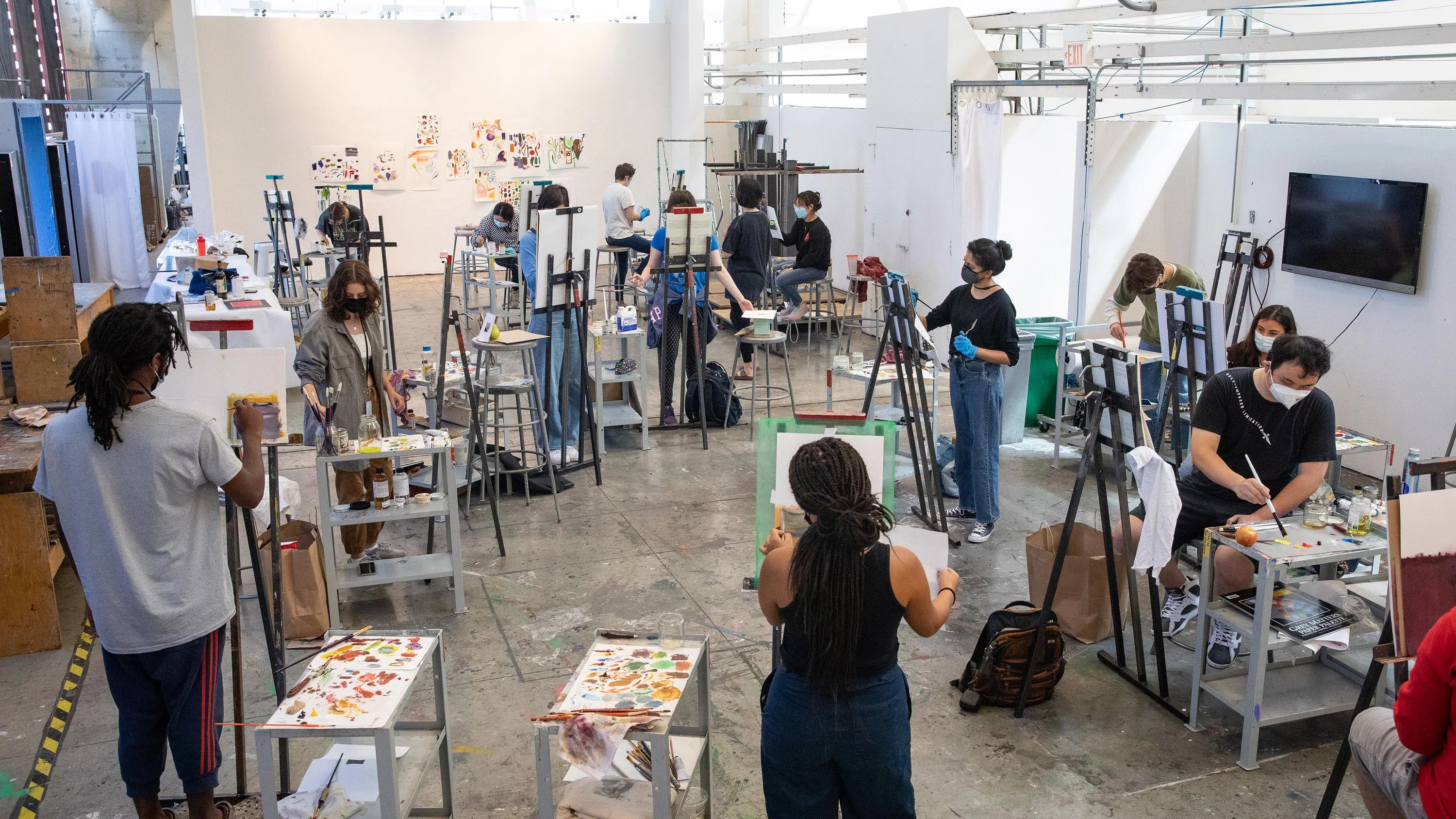 A painting class works on easels in a light-filled studio.