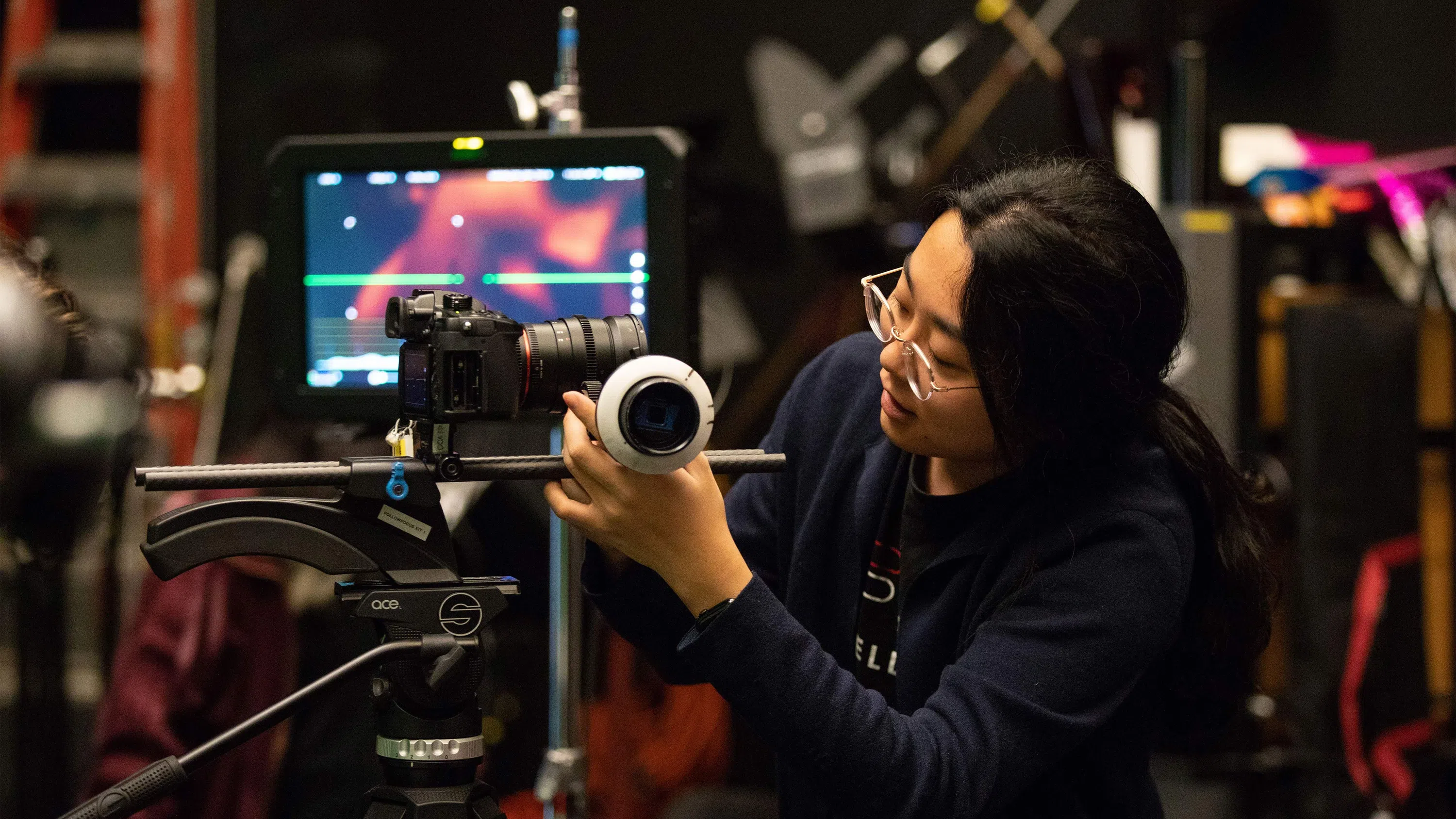Student adjusts a camera in a film production class.