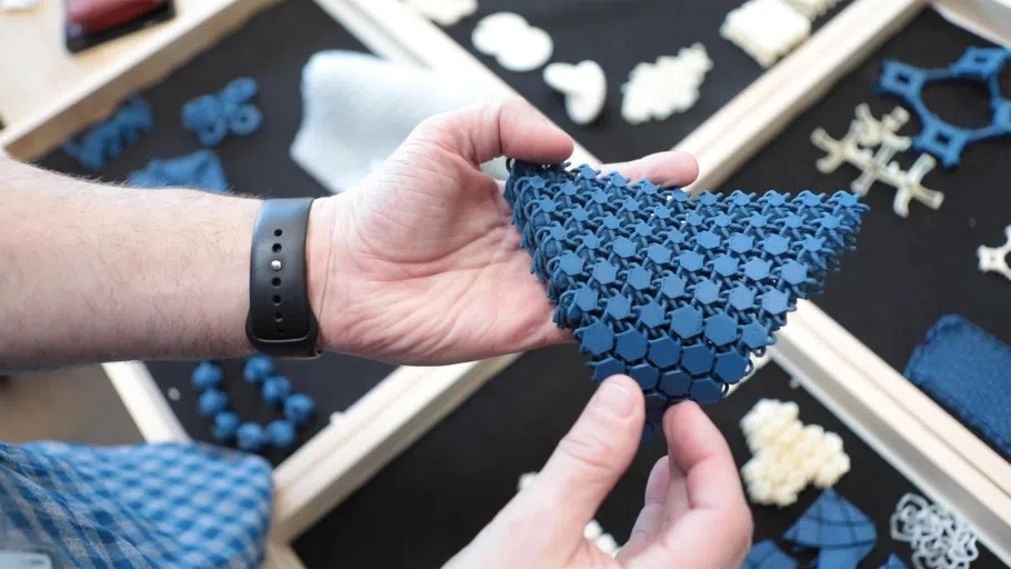 A close-up of hands holding a flexible fabric made on a 3D printer.