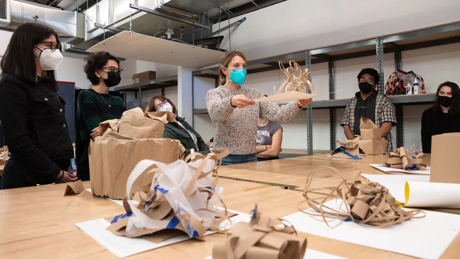 A class reviews table-top cardboard sculptures.