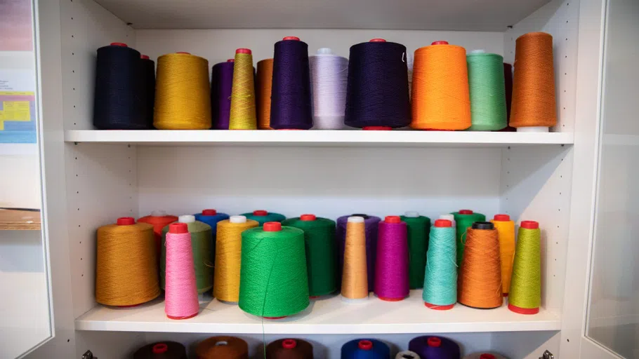 Dozens of colored yarn and thread in a cabinet.