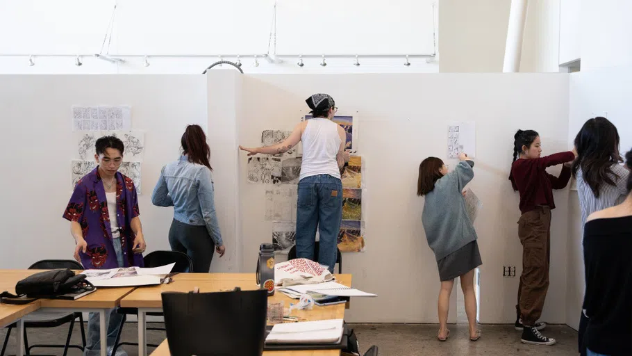 Five students pin up illustration work for a critique in the open Nave space.