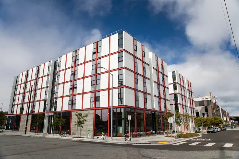 An exterior view of Founders Hall: A white building with red linear details.  