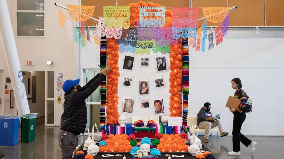 An altar composed of photos and perforated paper cut outs and flowers.