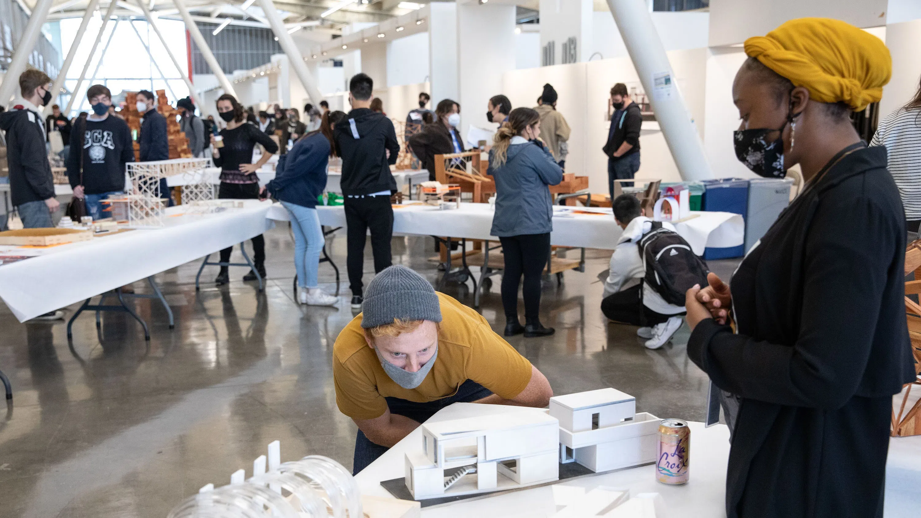 A student closely examines an architectural model within the crowded Nave.