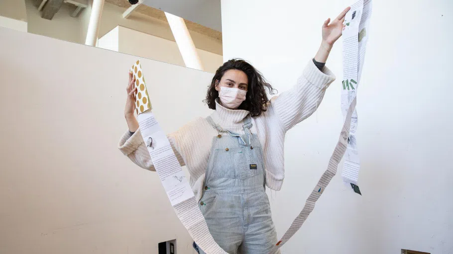 Emily Garcia (MFA Writing 2022) holds up an object, shaped like a banner, that she made in class.