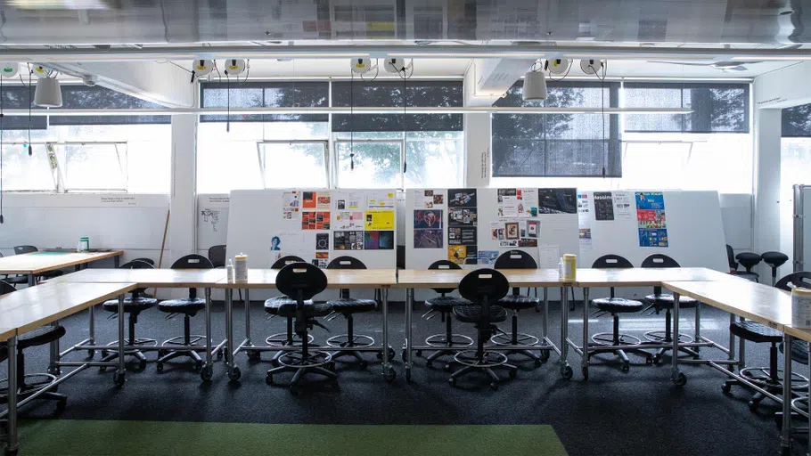 A gray-and-green carpeted room with modular desks, chairs, and rolling walls.