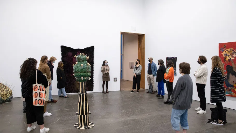 A dozen students standing in an art gallery.