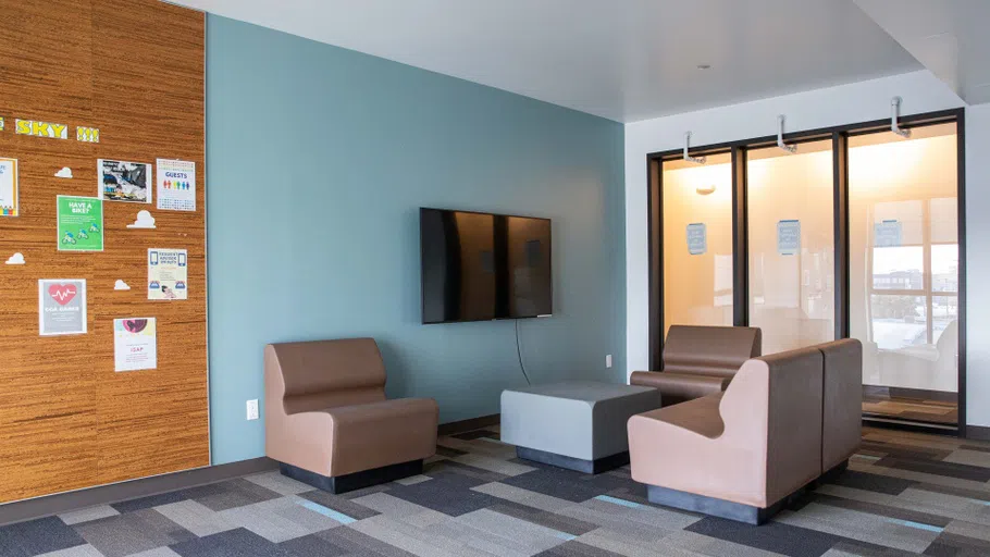 Two beige chairs are arranged around a flatscreen television in the student lounge.