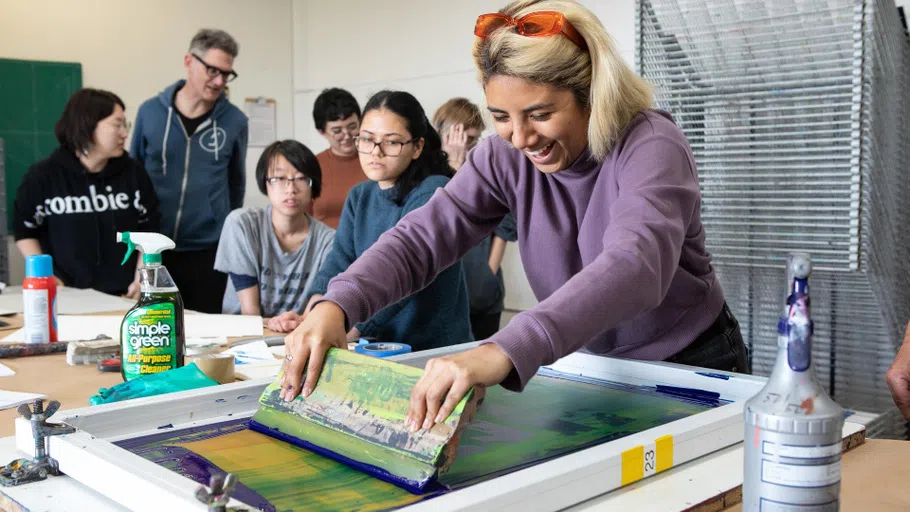 A student laughs while pulling a gradient print while a class watches.