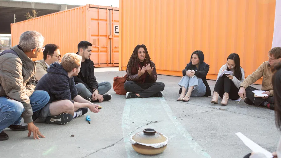 Students sit in a circle outside on CCA’s Backlot with Critical Ethnic Studies Chair Shylah Pacheco Hamilton in the center.